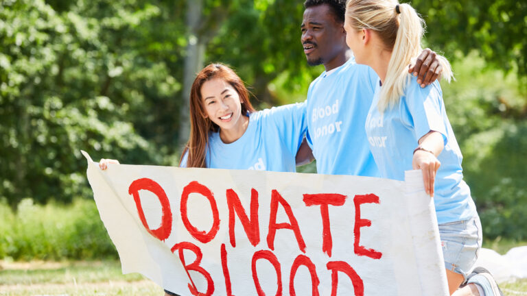 Teens holding a sign "Donate Blood"