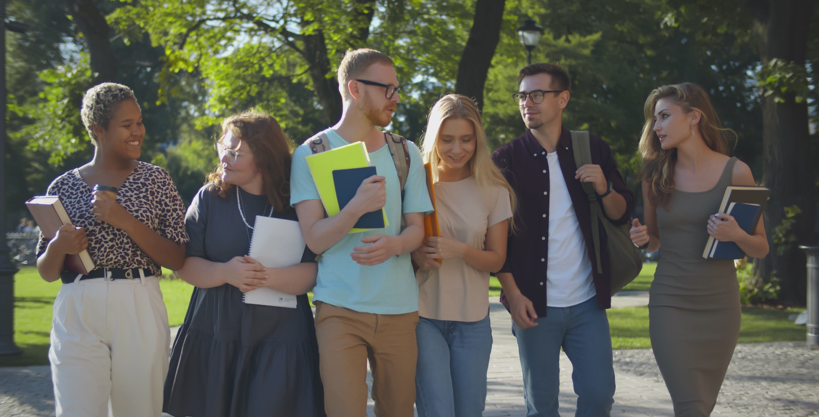 Group of young adults walking and chatting while on a campus.